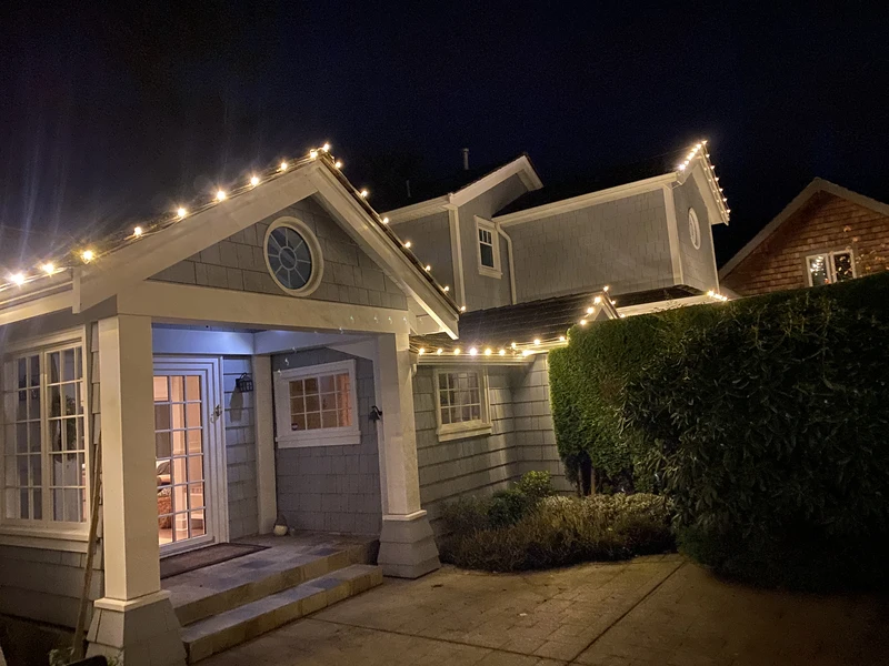 Holiday lighting installed discreetly on the eavestroughsa nd roofline of a house